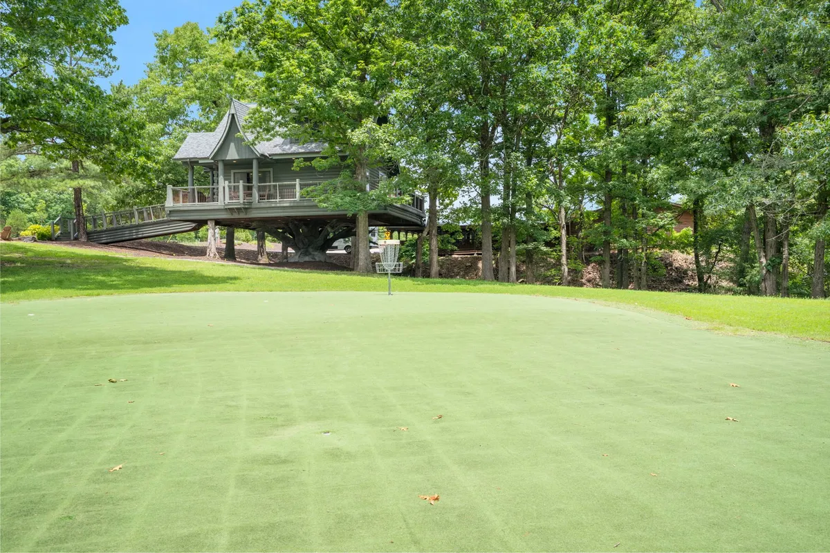 An exterior view of a house on stilts amidst lush greenery, with a golf putting green in the foreground. The setting feels open, peaceful, and seamlessly integrated with nature, suggesting opportunities for outdoor enjoyment and connection.