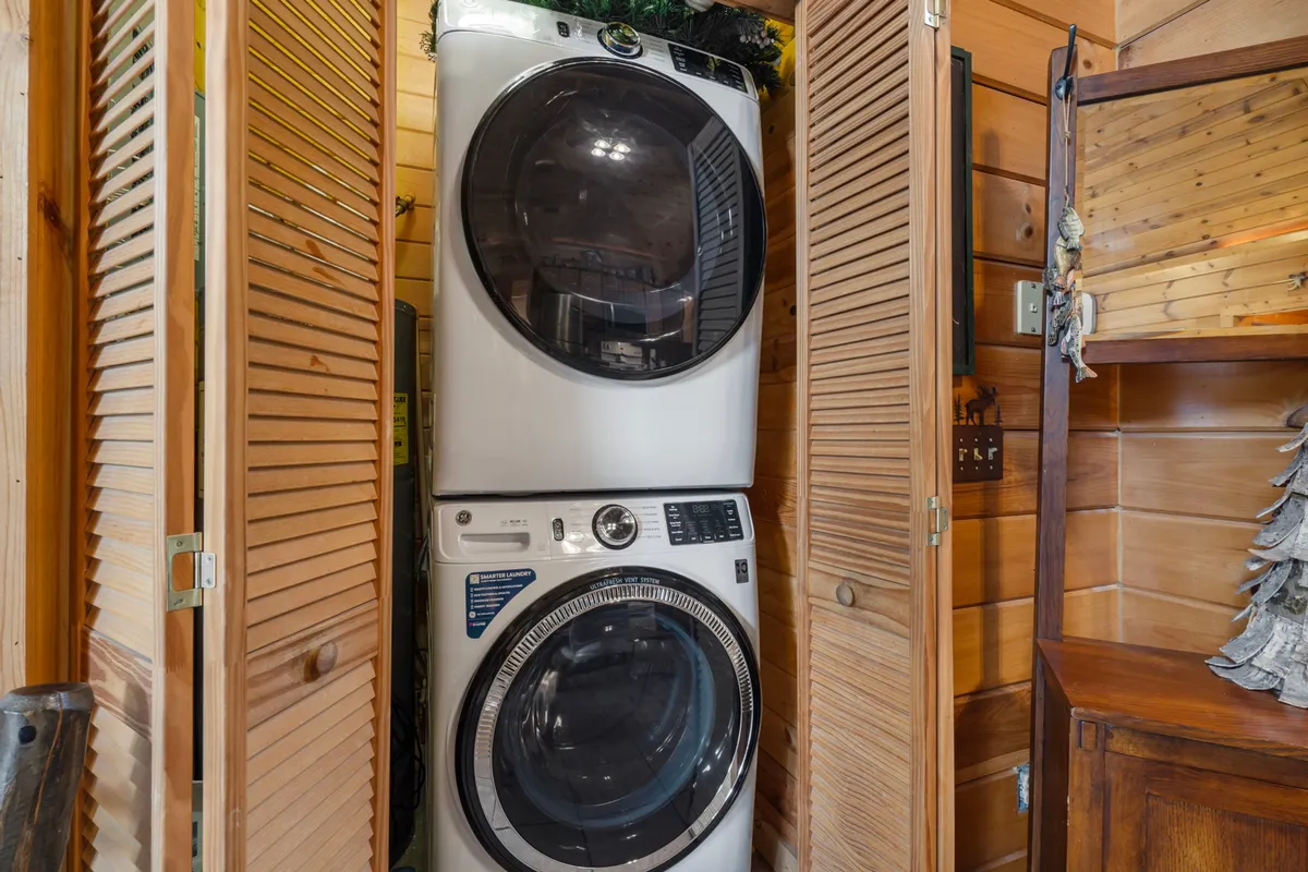A tidy and functional interior scene showing a stacked washer and dryer with wooden cabinetry and shuttered doors, representing in-home laundry facilities.