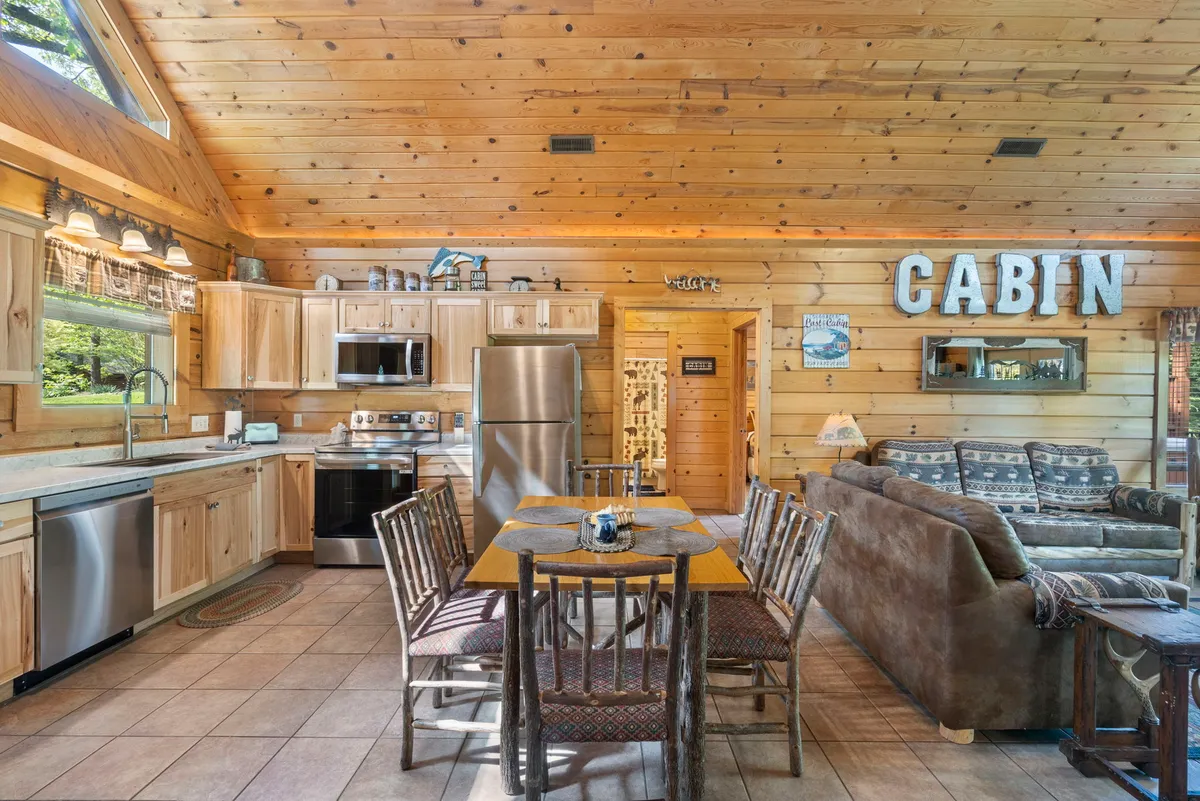 A cozy scene featuring a rustic wooden dining table adjacent to a comfortable sofa, with cabin-themed decor adding character. The layout supports both shared meals and relaxation, encouraging communal activities like games and conversations.